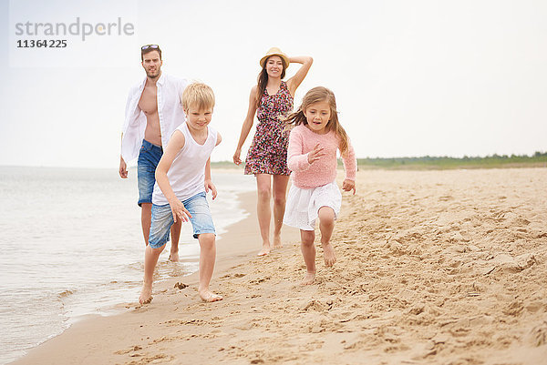 Familie läuft am Sandstrand entlang