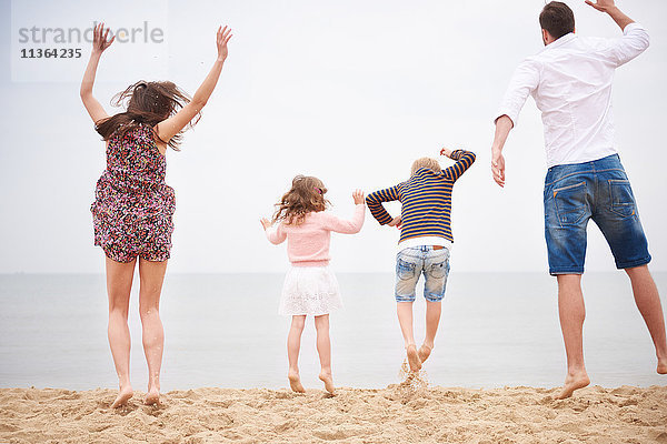 Familie springt am Strand