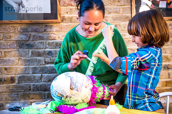 Mutter und Sohn schmücken Pinata zu Hause