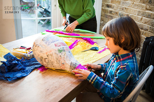 Mutter und Sohn schmücken Pinata zu Hause