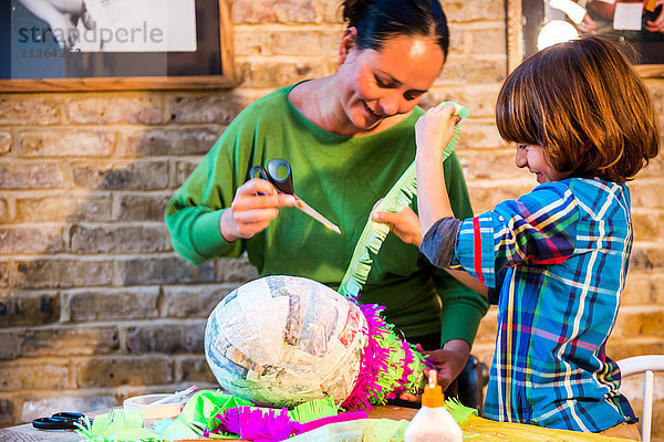 Mutter und Sohn schmücken Pinata zu Hause