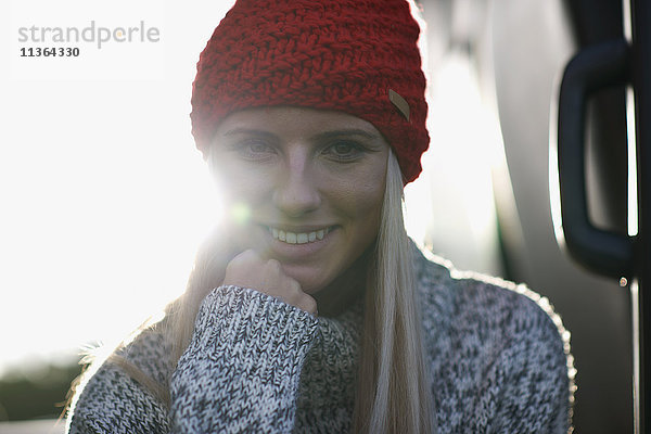 Sonnenlicht-Porträt einer jungen Frau mit roter Strickmütze