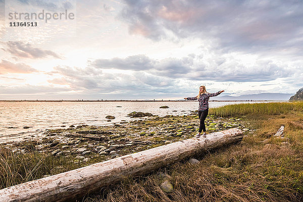 Frau balanciert auf einem Baumstamm am Wreck Beach  Vancouver  Kanada