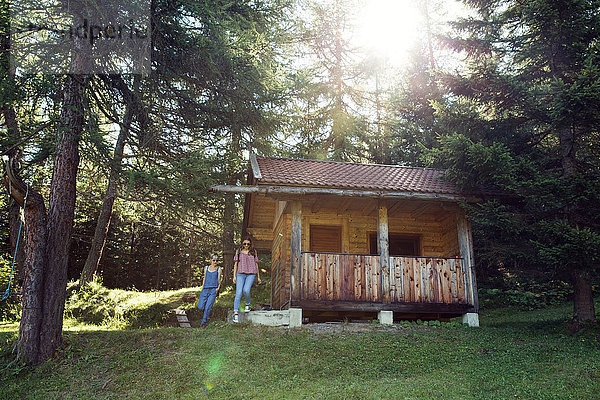 Zwei Freundinnen verlassen Blockhaus im Wald  Sattelbergalm  Tirol  Österreich