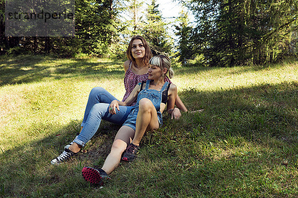 Zwei Freundinnen auf einer Waldlichtung liegend  Sattelbergalm  Tirol  Österreich