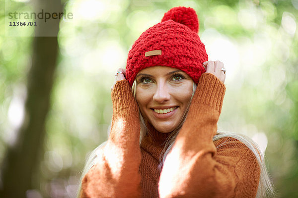 Porträt einer Frau mit Strickmütze  die Hände auf dem Kopf  wegguckend