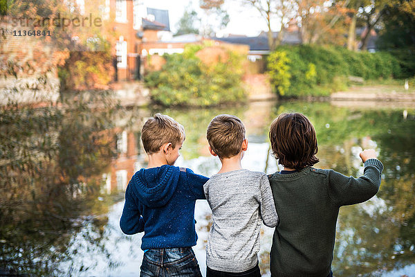 Drei kleine Jungen  am See stehend  Rückansicht