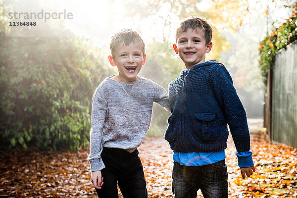 Porträt von Zwillingsjungen  im Freien  umgeben von Herbstlaub  lachend
