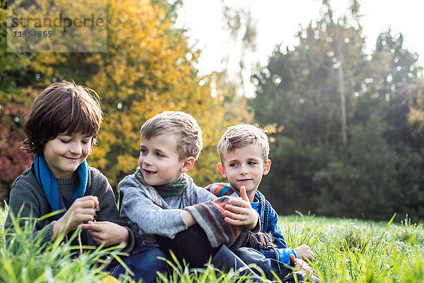 Drei Jungen sitzen zusammen auf dem Feld  im Herbst
