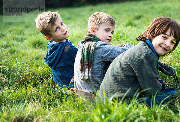 Porträt von drei Jungen  die zusammen auf dem Feld sitzen  im Herbst