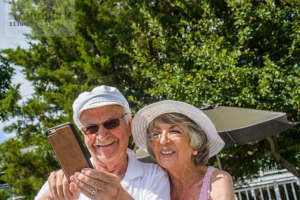 Glückliches älteres Ehepaar mit Mobiltelefon