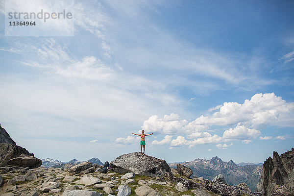 Junge Frau steht mit offenen Armen auf einem Felsen  Die Verzauberungen  Alpine Lakes Wilderness  Washington  USA