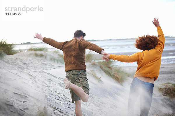 Ehepaar läuft Sanddünen hinunter zum Strand
