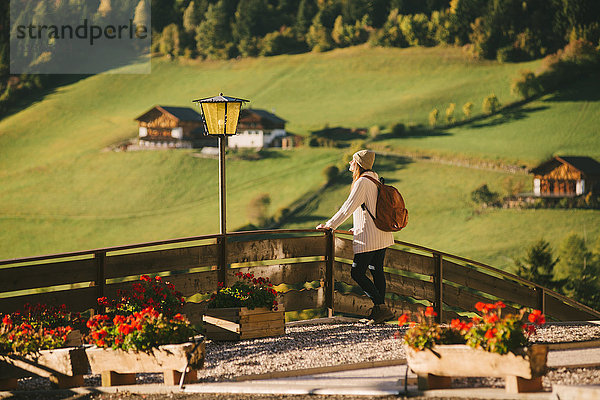 Frau geniesst Aussicht am Holzzaun  Santa Maddalena  Dolomiten  Val di Funes (Tal von Funes)  Südtirol  Italien