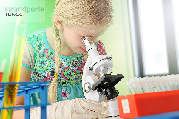 Mädchen  das sich als Wissenschaftlerin ausgibt und durch ein Mikroskop schaut