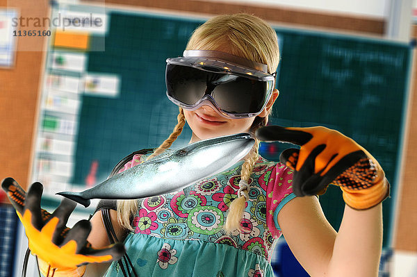 Mädchen  das sich als Lehrerin ausgibt und ein Virtual-Reality-Headset und Handschuhe trägt  um einen Wal zu zeigen