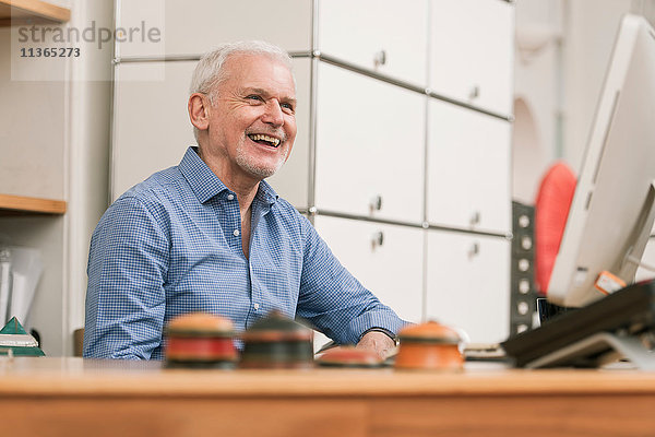 Älterer Mann lächelt am Arbeitstisch