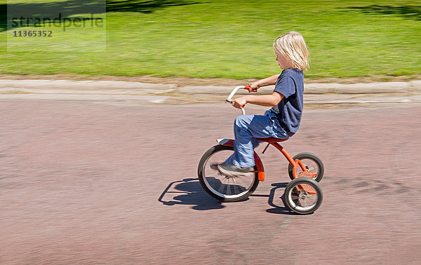 Seitenansicht eines Jungen auf einem Dreirad