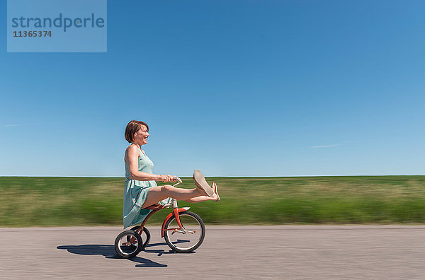 Seitenansicht einer Frau auf einem Dreirad in einer ländlichen Gegend