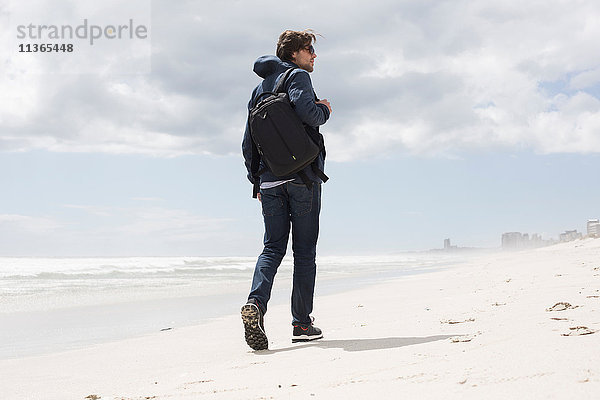Rückansicht eines jungen Mannes  der allein am Strand spazieren geht  Western Cape  Südafrika