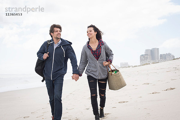Romantisches junges Paar beim Spaziergang am windgepeitschten Strand  Western Cape  Südafrika