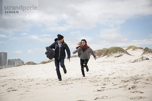 Junges Paar läuft am windgepeitschten Strand  Western Cape  Südafrika
