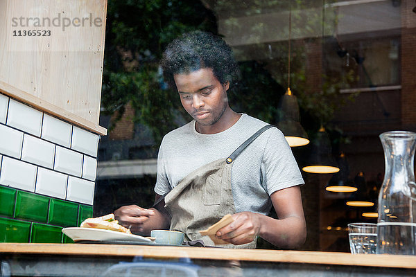 Kellner bei der Vorbereitung der Bestellung am Café-Fenster