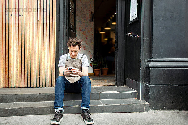 Kellner macht eine Pause auf Cafe Schritt Blick auf Smartphone