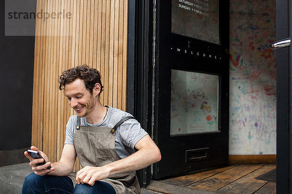 Kellner macht eine Pause auf Cafe Schritt Blick auf Smartphone