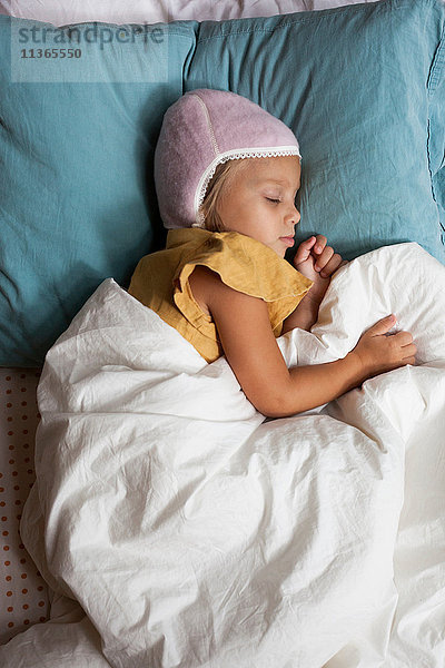 Junges Mädchen schläft im Bett und trägt einen warmen Hut