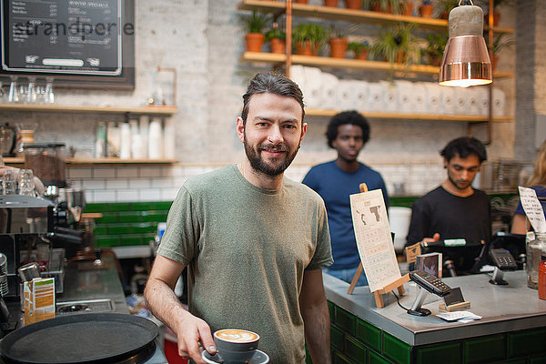 Porträt eines männlichen Barista  der Kaffee im Café serviert.
