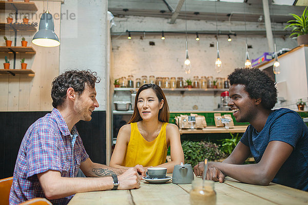 Frau und männliche Freunde chatten zusammen im Café