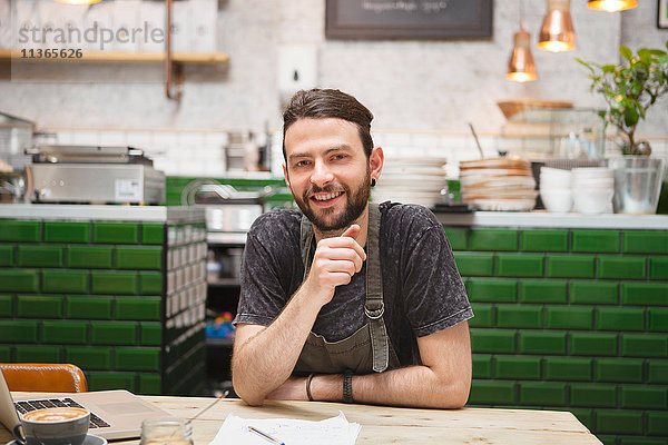 Porträt eines männlichen Cafébesitzers  der Papierkram am Tisch erledigt