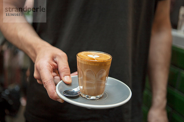 Ein Schuss Barista mit einem Glas Kaffee im Cafe.