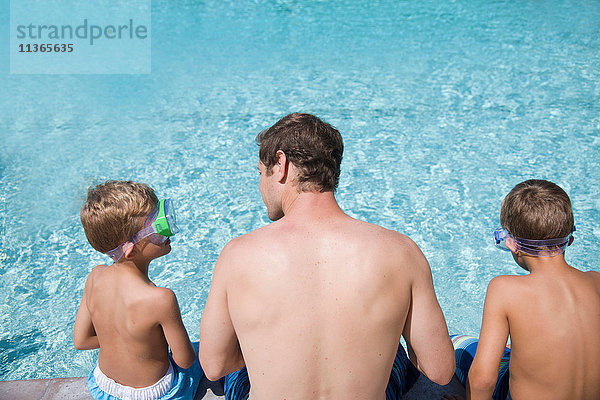 Rückansicht eines Mannes und zweier Söhne  die mit einer Taucherbrille am Pool sitzen  Laguna Beach  Kalifornien  USA