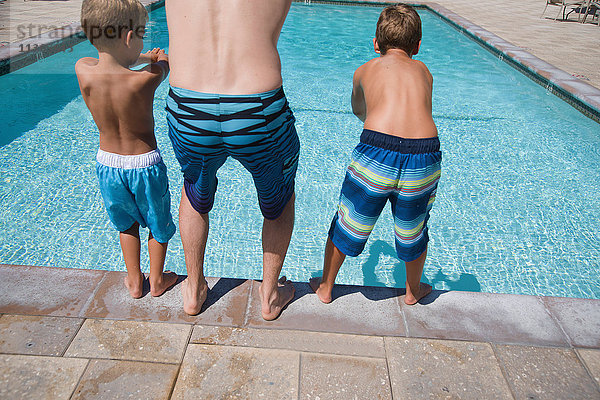 Rückansicht eines Mannes und zweier Söhne  die am Pool tauchen üben  Laguna Beach  Kalifornien  USA