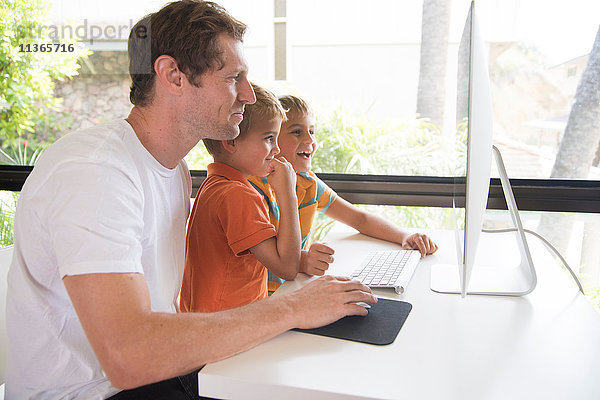 Mann und zwei Söhne mit Desktop-Computer