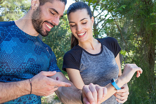 Männliche und weibliche Läufer bei der Kontrolle von Smartwatches im Park  Split  Dalmatien  Kroatien