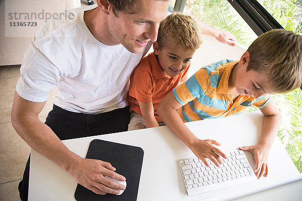 Mann und zwei Söhne beim Tippen auf der Desktop-Computertastatur