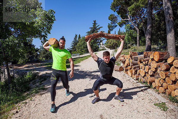 Zwei junge Männer machen Gewichthebertraining mit Baumstämmen im Wald  Split  Dalmatien  Kroatien