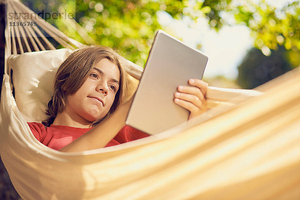 Teenager-Junge in der Gartenhängematte mit digitalem Tablett-Touchscreen