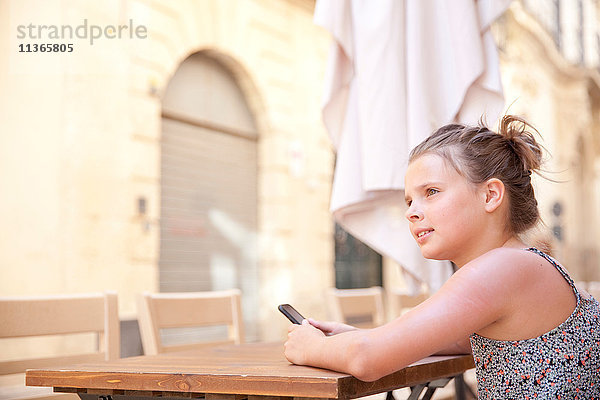 Junges Mädchen benutzt Mobiltelefon bei Tisch  Lecce  Italien