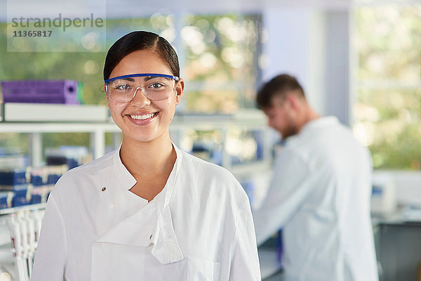 Wissenschaftlerin mit Schutzbrille lächelt in die Kamera