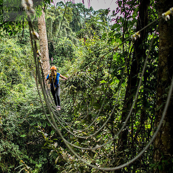 Frau überquert Seilbrücke im Wald  Ban Nongluang  Provinz Champassak  Paksong  Laos