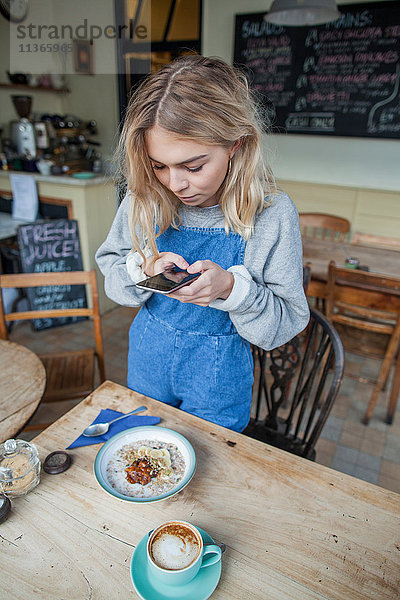 Junge Frau im Cafe  mit Smartphone