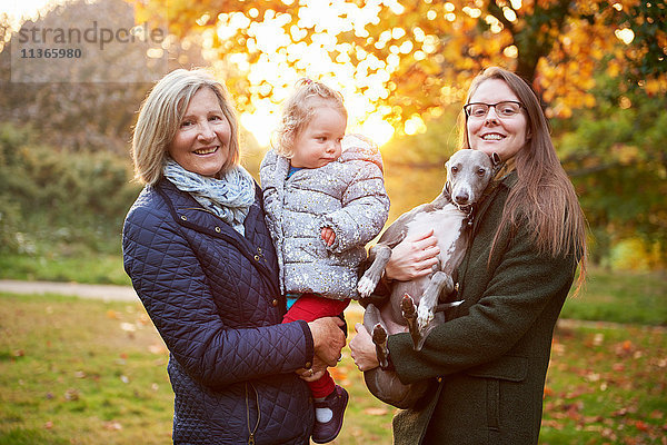 Porträt einer älteren Frau mit Tochter  Enkelin und Hund im Herbstpark