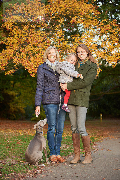 Porträt einer älteren Frau  einer Tochter  einer Enkelin und eines Hundes im Herbstpark