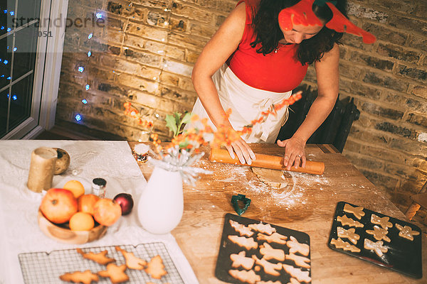 Reife Frau rollt Weihnachtsplätzchen an der Küchentheke