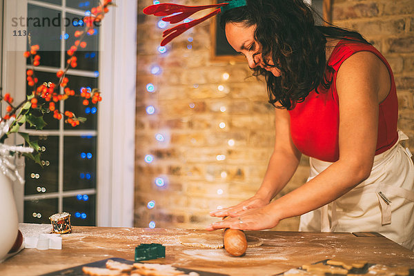 Reife Frau rollt Weihnachtsplätzchen an der Küchentheke