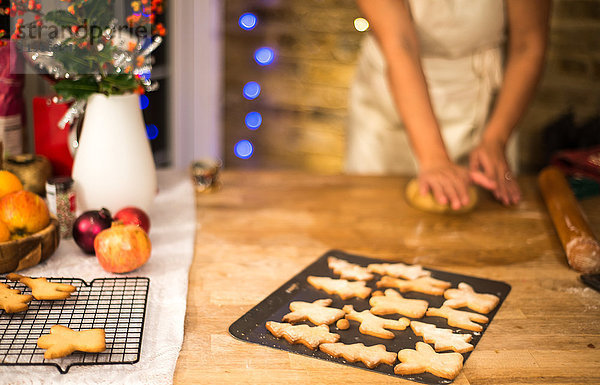 Mittelteil einer Frau  die Weihnachtsplätzchen an der Küchentheke plättet